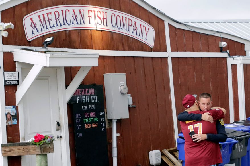 A man hugs a police officer in front of the American Fish Company following a fatal shooting that occurred the night before, Sept. 28, 2025, in Southport, N.C. (AP Photo/Chris Seward, File)