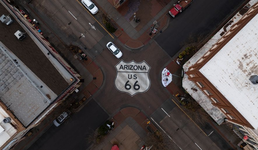 Motorists travel through an intersection marked with a U.S. 66 shield in Winslow, Ariz., a town on the historic highway, Thursday, Nov. 20, 2025. (AP Photo/Jae C. Hong)