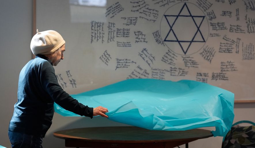 Volunteer Marlene Ring spreads a table cloth while preparing a room for a passover meal Monday, March 30, 2026, at the Beth Israel Synagogue in Waterville, Maine. (AP Photo/Robert F. Bukaty)
