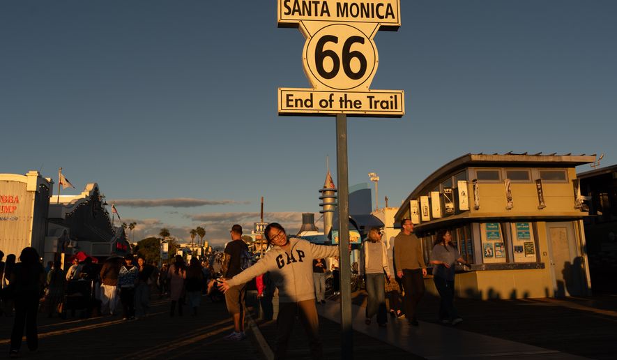 FILE - A visitor poses for photos with the "End of the Trail" Route 66 sign on the Santa Monica Pier in Santa Monica, Calif., Saturday, Nov. 22, 2025. (AP Photo/Jae C. Hong, File)