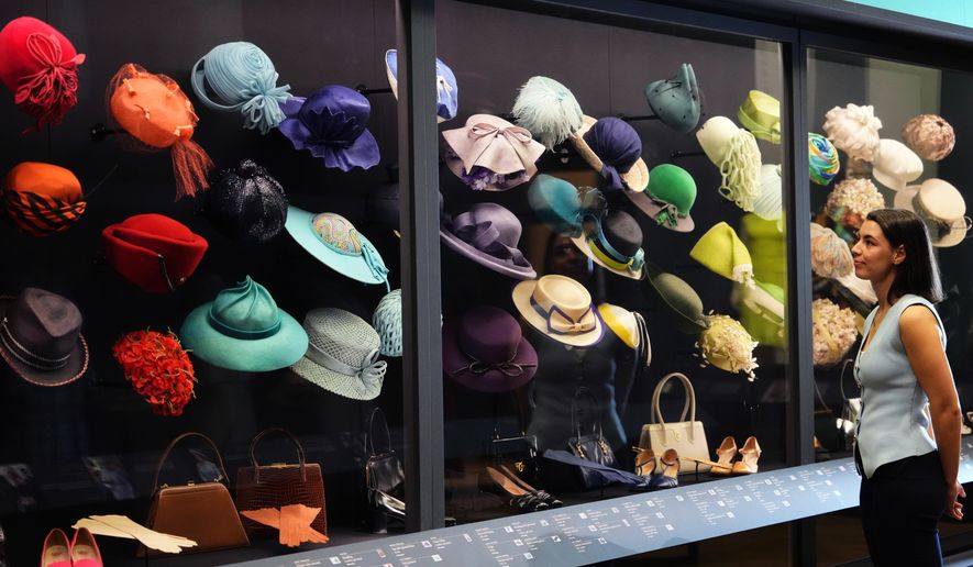 A member of the Royal Collection Trust staff looks towards hats, bags and shoes worn by Princess Elizabeth, on display at 'Queen Elizabeth II: Her Life in Style' exhibition, to mark the centenary of the late queen's birth, at The King's Gallery at Buckingham Palace in London, Thursday, April 9, 2026. (AP Photo/Kirsty Wigglesworth)