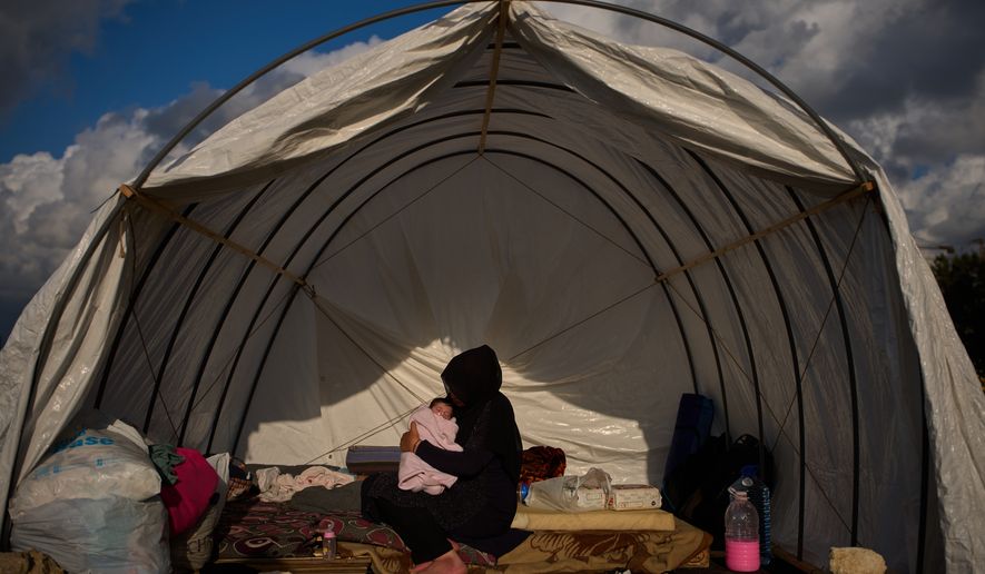 Haifa Kenjo, who fled Israeli airstrikes on the southern suburbs of Beirut, holds her 15-day-old daughter Shiman inside the tent she uses as a shelter and where she gave birth to her in Beirut, Sunday, April 12, 2026. (AP Photo/Emilio Morenatti)