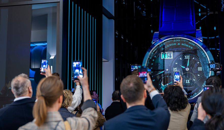 Visitors take photos with their smartphones of a watch at the German watch manufacturer A. Lange & Shone stand, during the opening day of the "Watches and Wonders Geneva" luxury watch fair, in Geneva, Switzerland, Tuesday, April 14, 2026. (Salvatore Di Nolfi/Keystone via AP)
