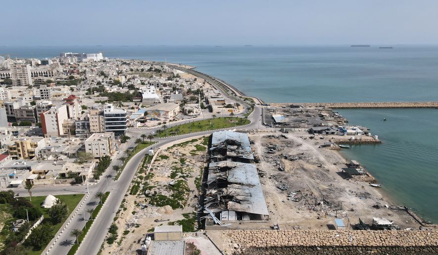 Backdropped by ships in the Strait of Hormuz, damage, according to local witnesses caused by several recent airstrikes during the U.S.-Israel military campaign, is seen on a fishing pier in the port of Qeshm island, Iran, Monday, April 13, 2026. (AP Photo/Asghar Besharati)