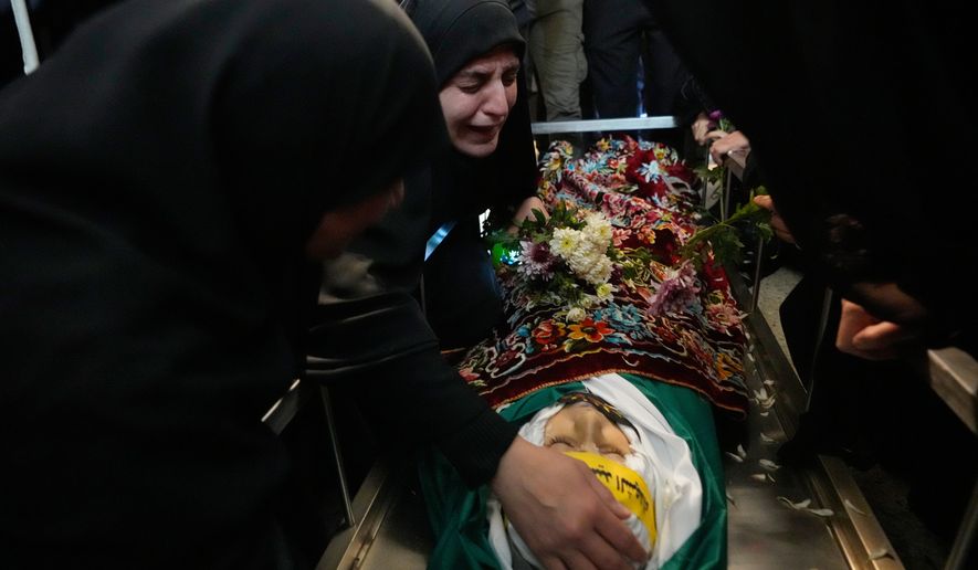FILE — Malak Meslmani, center, the mother of Jawad Younes, 11, who was was killed in an Israeli airstrike, mourns over her son's body during his funeral procession in Saksakieh village, south Lebanon, Saturday, March 28, 2026. (AP Photo/Hussein Malla, File)