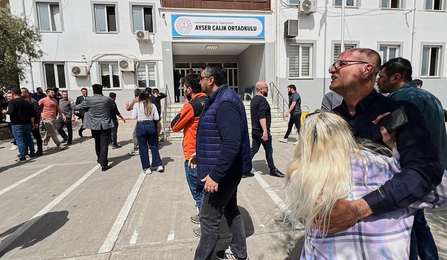 People stand at the courtyard of a secondary school where an assailant opened fire, in Kahramanmaras, Turkey, Wednesday, April 15, 2026, (IHA via AP)