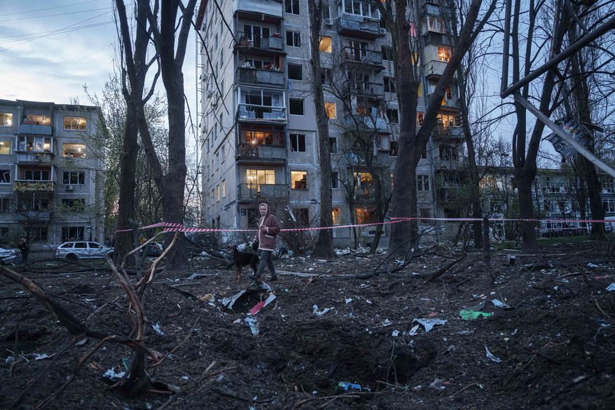 A woman with a dog walks among the rubble of a house damaged after a Russian strike on residential area in Kyiv, Ukraine, on Thursday, April 16, 2026. (AP Photo/Evgeniy Maloletka)
