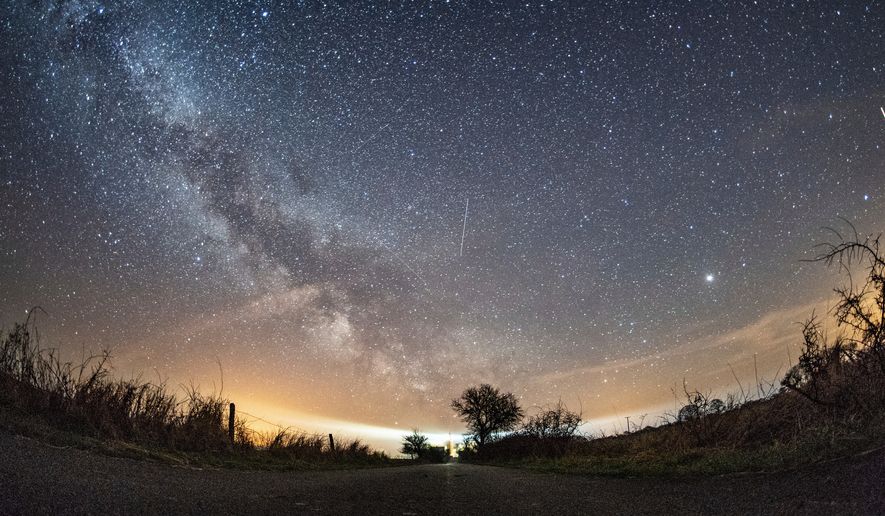The milky way and traces of meteors illuminate the sky over Burg on the Baltic Sea island of Fehmarn, northern Germany, April 20, 2018. (Daniel Reinhardt/dpa via AP, File)