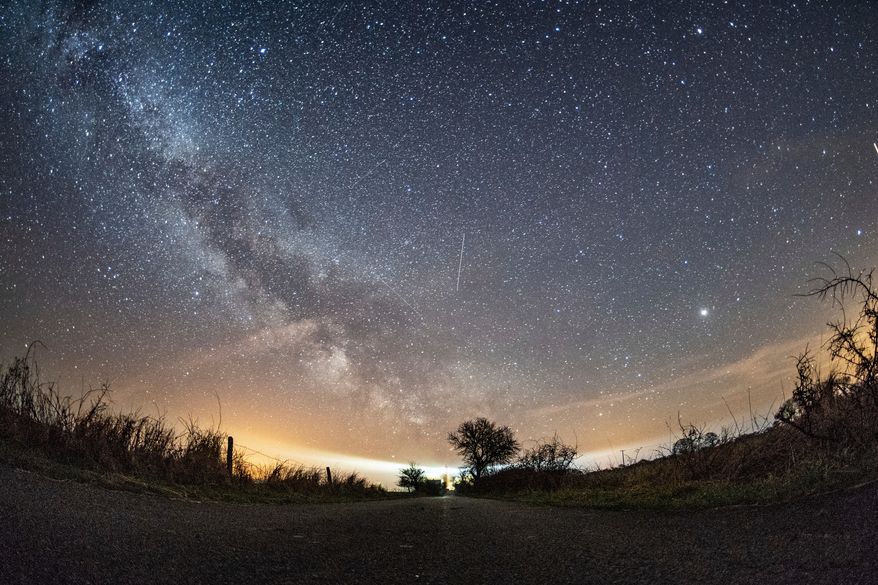 The milky way and traces of meteors illuminate the sky over Burg on the Baltic Sea island of Fehmarn, northern Germany, April 20, 2018. (Daniel Reinhardt/dpa via AP, File)