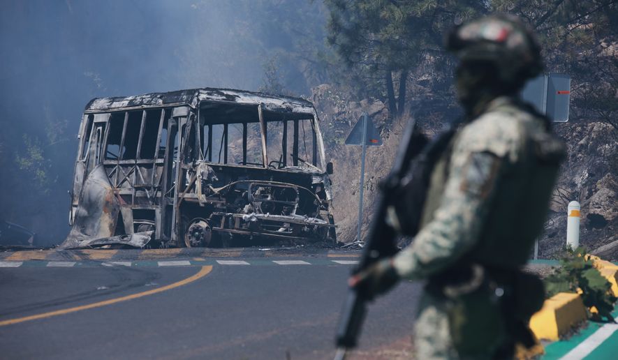 A soldier stands guard by a charred vehicle after it was set on fire, in Cointzio, Michoacán state, Mexico, Sunday, Feb. 22, 2026, following the death of the leader of the Jalisco New Generation Cartel, Nemesio Oseguera, known as "El Mencho." (AP Photo/Armando Solis) **FILE**