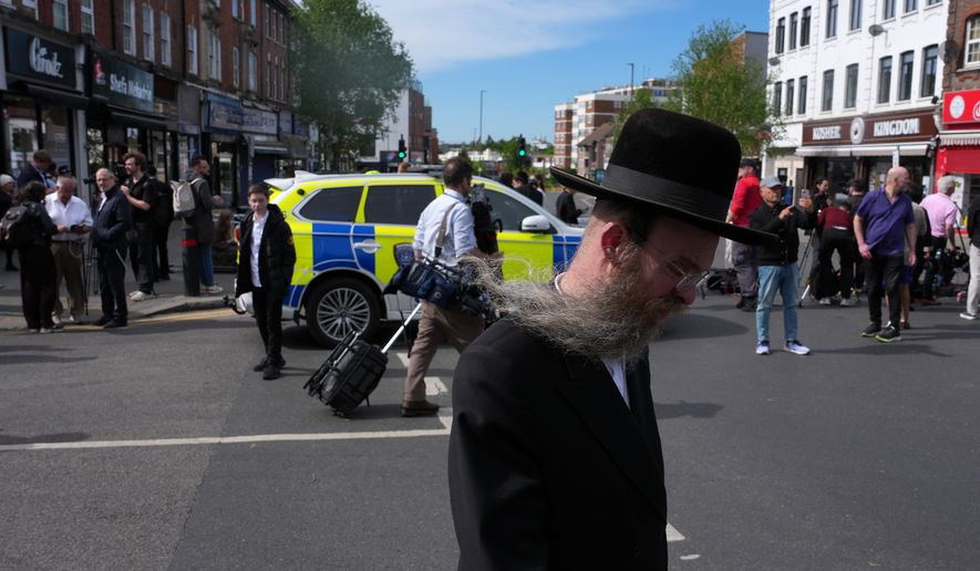 A man walks past a blocked road after two people were stabbed in Golders Green neighbourhood, that has a large Jewish community, in London, Wednesday, April 29, 2026.(AP Photo/Kin Cheung)