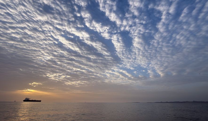 The sun rises behind a tanker anchored in the Strait of Hormuz off the coast of Qeshm Island, Iran, Saturday, April 18, 2026. (AP Photo/Asghar Besharati, File)