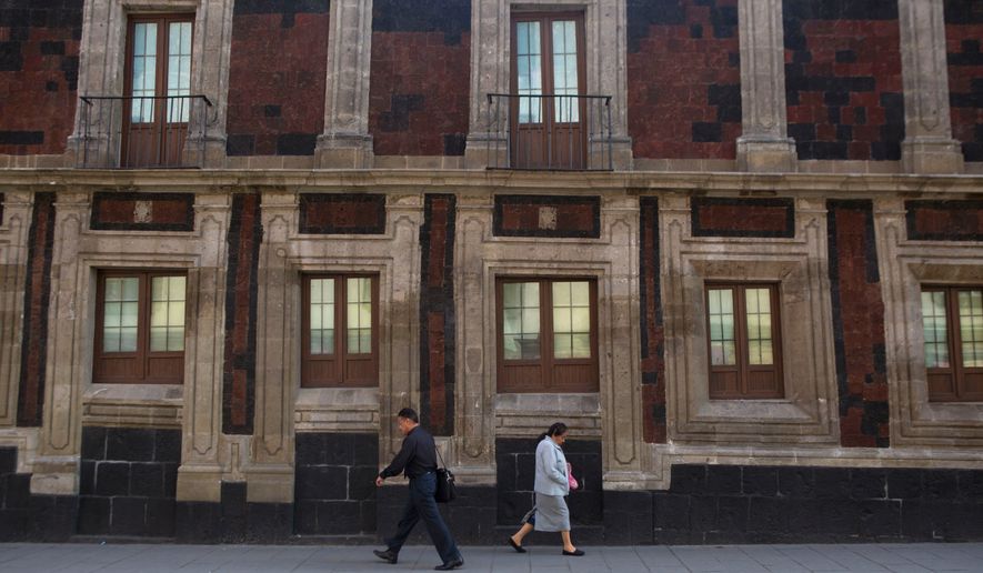 FILE - Pedestrians walk past a slightly tilted historic building in downtown Mexico City, June 15, 2016. The city was built on a drained lake bed and many buildings are noticeably tilted, from sinking unevenly into the soft earth over decades or centuries. (AP Photo/Rebecca Blackwell, File)