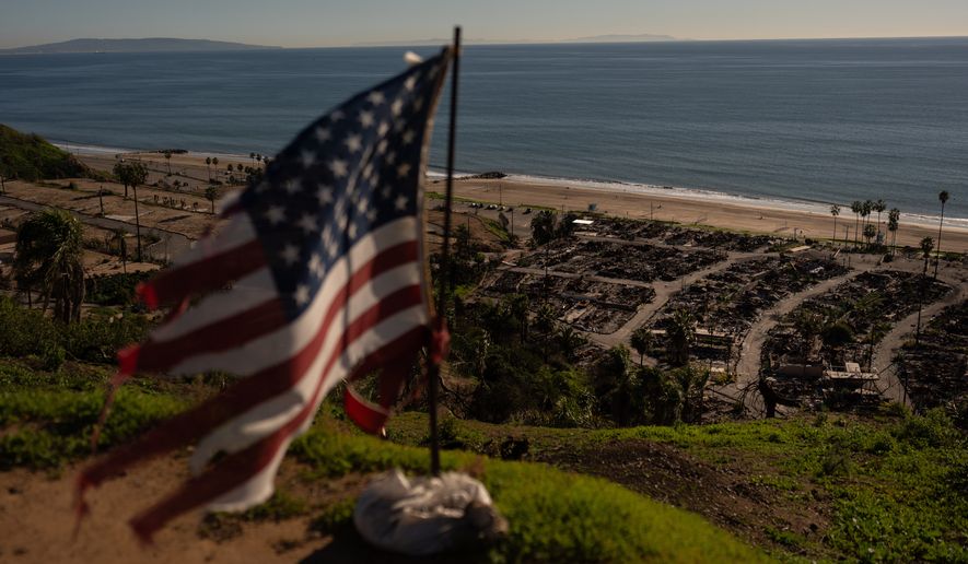 A tattered U.S. flag flaps in the wind over the remains of a mobile home park that was destroyed in the Palisades Fire along the Pacific Ocean, Dec. 5, 2025, in the Pacific Palisades neighborhood of Los Angeles. (AP Photo/Jae C. Hong, file)