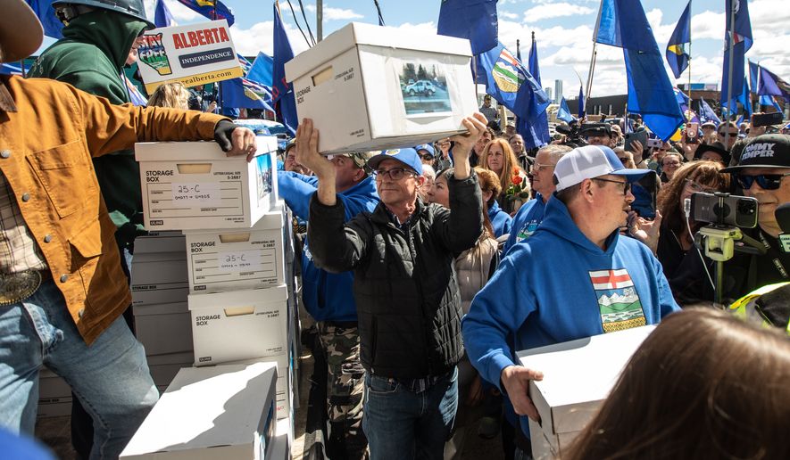 Supporters carry boxes of signatures to submit for a separation referendum to Elections Alberta in Edmonton, on Monday, May 4, 2026. (Jason Franson/The Canadian Press via AP)