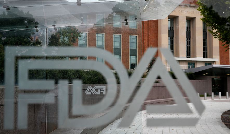 FILE - The U.S. Food and Drug Administration building is seen behind FDA logos at a bus stop on the agency's campus in Silver Spring, Md., Aug. 2, 2018. (AP Photo/Jacquelyn Martin, File)