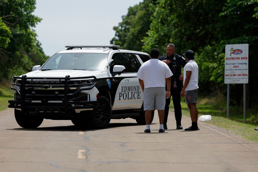 Police talks to two guys at the entrance to Scissortail Campground at Arcadia Lake in Edmond, Okla. who are wanting to get their belongings from the campground on Monday, May 4, 2026 after a party shooting on Sunday evening. (AP Photo/Alonzo Adams)