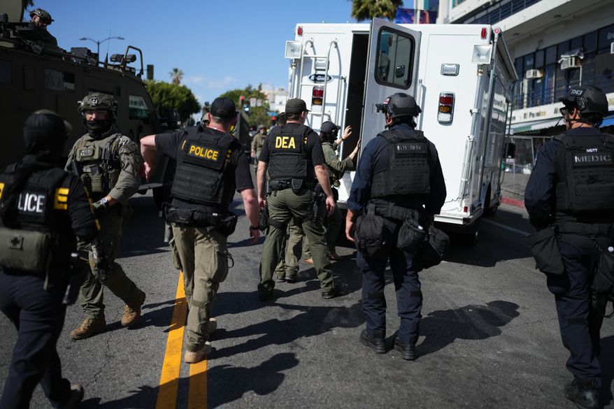 Drug Enforcement Administration (DEA) agents alongside other law enforcement officers work the scene near MacArthur Park after federal authorities made arrests on charges related to selling illicit drugs on Wednesday, May 6, 2026, in Los Angeles. (AP Photo/Jae C. Hong)
