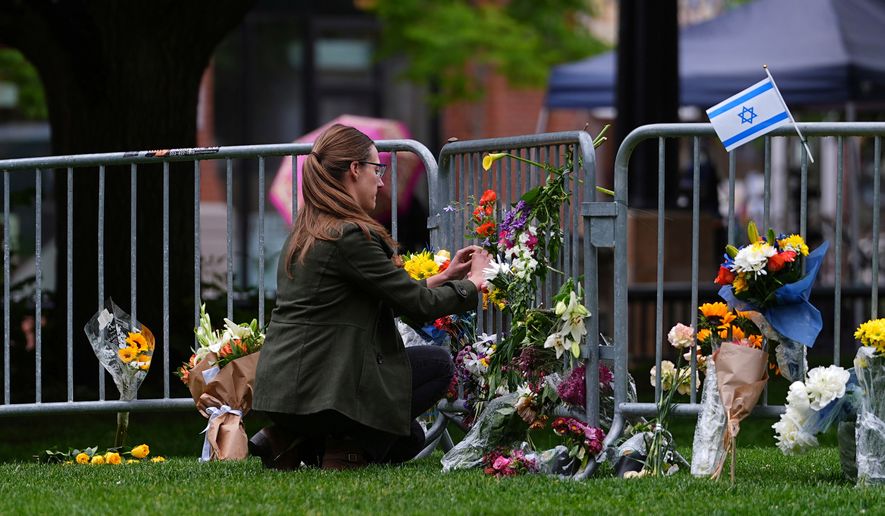 A woman places a bouquet of flowers at a makeshift memorial for victims of an attack outside of the Boulder County, Colo., courthouse Tuesday, June 3, 2025, in Boulder, Colo. (AP Photo/David Zalubowski, File)