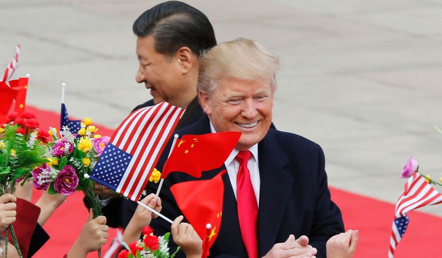FILE - U.S. President Donald Trump, right, and Chinese President Xi Jinping are greeted by children waving flowers and flags during a welcome ceremony at the Great Hall of the People in Beijing, Nov. 9, 2017. (AP Photo/Andy Wong, File)