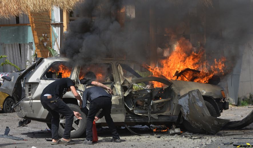 A person is seen inside a burning vehicle as men attempt to put out the fire after an Israeli airstrike hit a car in the coastal town of Barja, south of Beirut, Lebanon, Wednesday, May 13, 2026. (AP Photo/Mustafa Jamalddine)