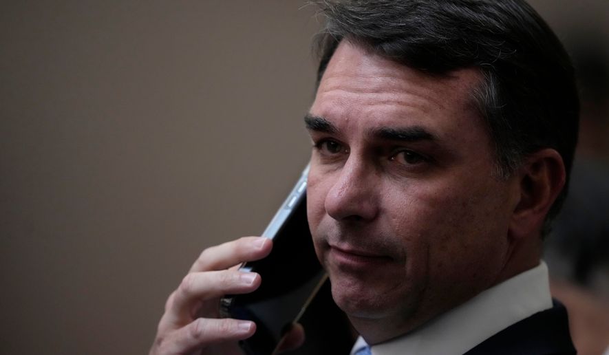 Sen. Flavio Bolsonaro, son of former Brazilian President Jair Bolsonaro, talks on the phone as he arrives for the swearing-in ceremony for justices Nunes Marques and Andre Mendonca as president and vice president of Brazil's Superior Electoral Court in Brasilia, Brazil, Tuesday, May 12, 2026. (AP Photo/Eraldo Peres)