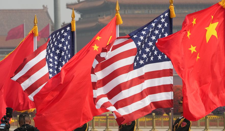 Members of the military honor guard hold American and Chinese flags before President Donald Trump is greeted by Chinese President Xi Jinping at a welcome ceremony at the Great Hall of the People, Thursday, May 14, 2026, in Beijing. (AP Photo/Mark Schiefelbein)