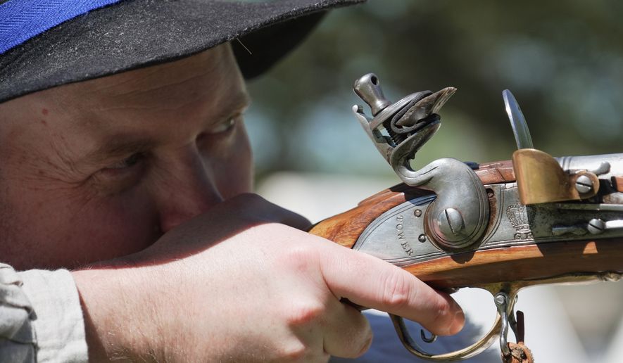 A.J. Drake, a historic interpreter, aims his Brown Bess flintlock replica musket during a Revolutionary War event in Halifax, N.C., on April 10, 2026. (AP Photo/Allen G. Breed)