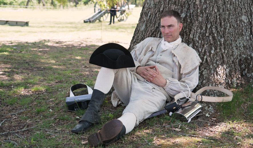 Army officer Jason Monhollen rests beneath a tree during a Revolutionary War event, in which he portrays a private in the 2nd North Carolina Infantry Regiment, in Halifax, N.C., on April 11, 2026. (AP Photo/Allen G. Breed)