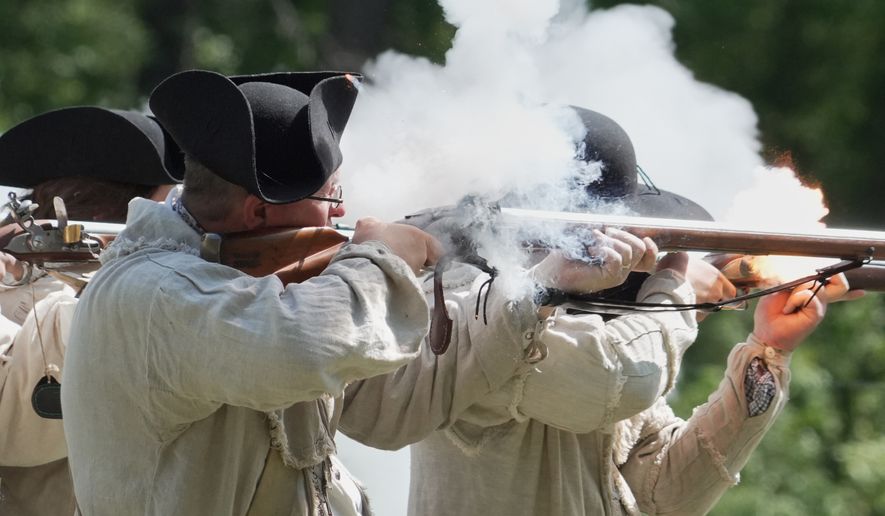 Re-enactors fire a volley with their flintlock muskets during a Revolutionary War event in Halifax, N.C., on April 11, 2026. (AP Photo/Allen G. Breed)