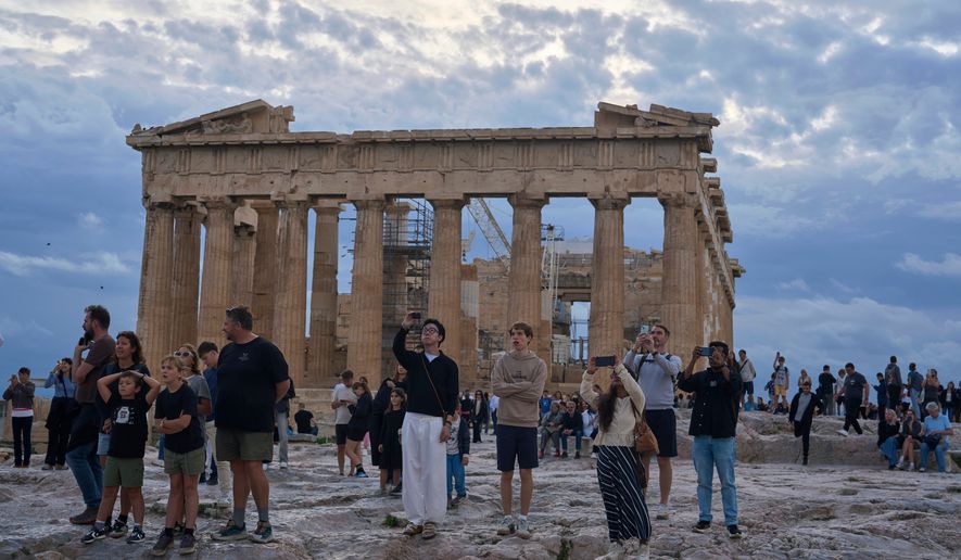 FILE - Tourists visit the Acropolis hill with he 5th century B.C. Parthenon, in Athens, Friday, Oct. 31, 2025. (AP Photo/Petros Giannakouris, File)