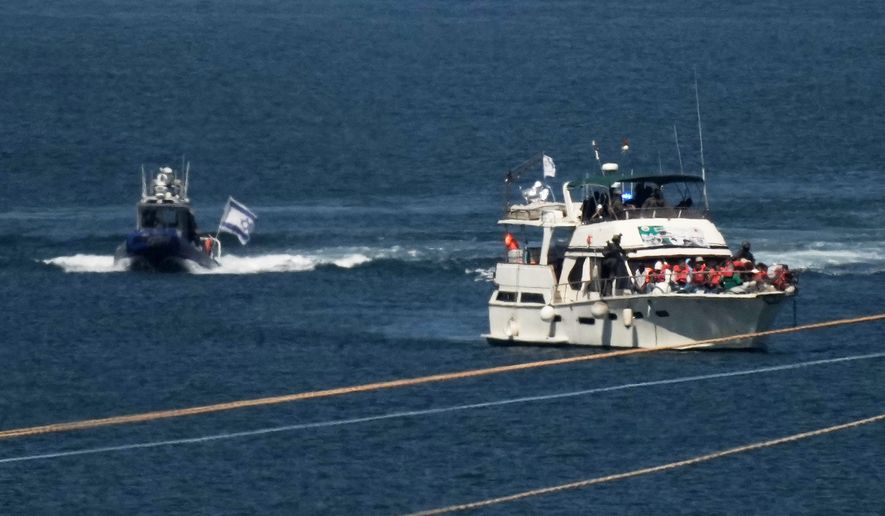 FILE - Activists in orange life jackets sit aboard a Gaza-bound Sumud Flotilla boat as Israeli navy soldiers sail it into the port of Ashdod, Israel, Oct. 2, 2025, after it was intercepted while approaching the Gaza coast. (AP Photo/Leo Correa, file)