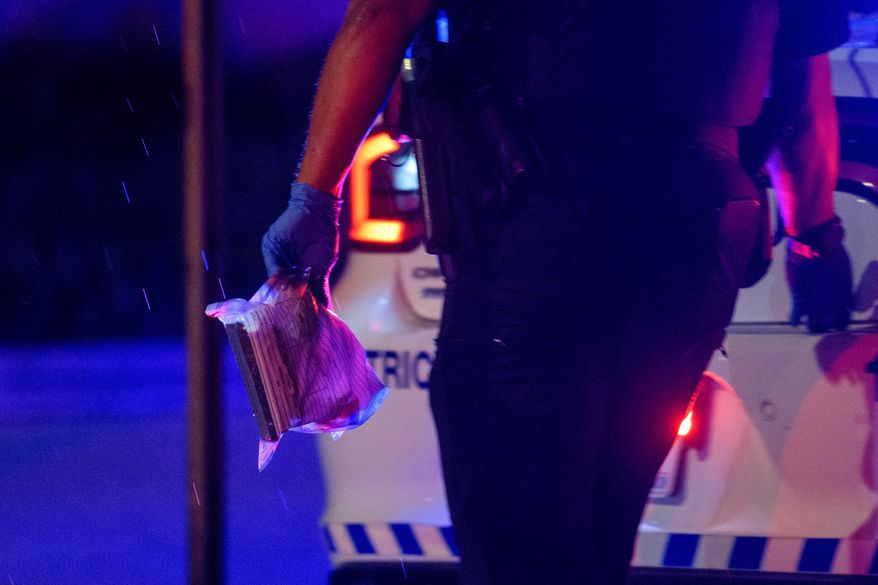 A Washington D.C. Metro police office carries an evidence bag to his car as law enforcement work the scene after two staff members of the Israeli Embassy in Washington were shot and killed outside the Capital Jewish Museum, May 22, 2025, in Washington. (AP Photo/Rod Lamkey, Jr., File)