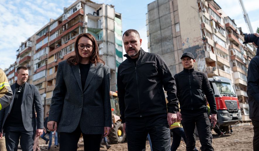 Ukraine's Prime Minister Yuliia Svyrydenko, left, and Ukraine's Interior Minister Ihor Klymenko, right, walk in the yard of an apartment building heavily damaged after a Russian strike on residential neighbourhood in Kyiv, Ukraine, on Friday, May 15, 2026. (AP Photo/Evgeniy Maloletka)