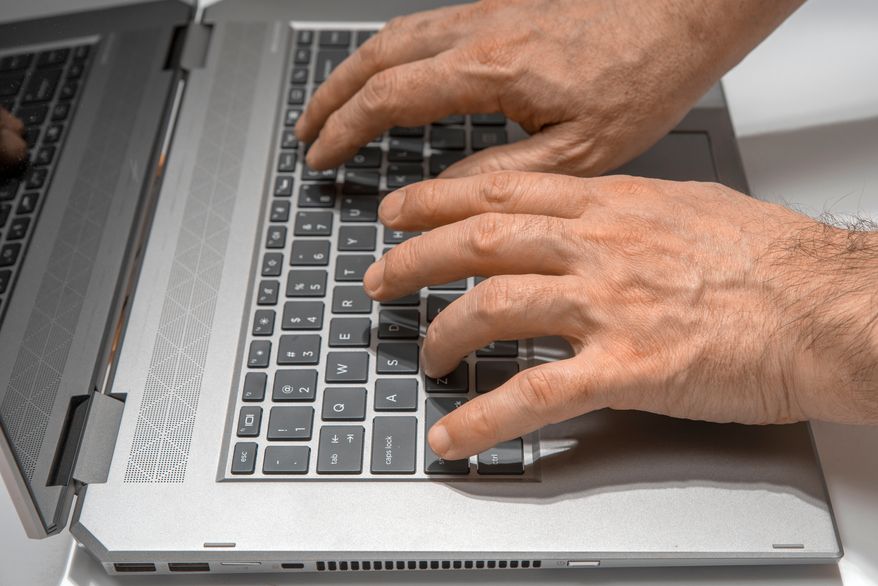Man's hands typing on a laptop keyboard. File photo credit: TSViPhoto via Shutterstock.