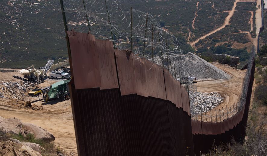 Construction crews work on a new border wall segment near the end of a previously built section on Kuuchamaa Mountain, Friday, April 24, 2026, seen from Tecate, Mexico. (AP Photo/Gregory Bull)