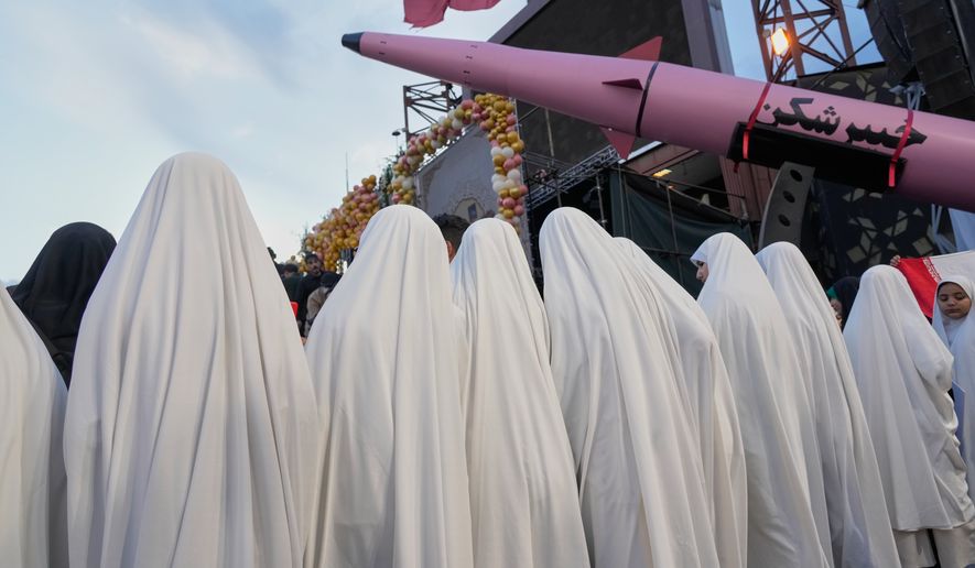 A group of girls stand beside a "Khaybar-buster" missile during a mass wedding ceremony for couples participating in the "Janfada" ("Sacrifice for Iran") pro-government campaign in Tehran, Iran, Monday, May 18, 2026. (AP Photo/Vahid Salemi)