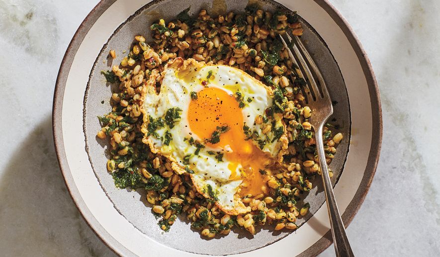 This image released by Voracious shows a recipe for a fried egg with greens and grains in a garlic herb sauce from the cookbook “Cook90,” by David Tamarkin. (Chelsea Kyle/Voracious via AP)