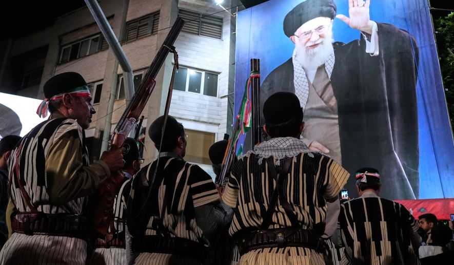 Bakhtiari nomads, wearing traditional dress, hold their guns during a pro-government gathering near the residence where former Iranian Supreme Leader Ayatollah Ali Khamenei, shown on a banner, was killed in U.S. and Israeli strikes on Feb. 28, in Tehran, Iran, Monday, May 18, 2026. (AP Photo/Vahid Salemi)