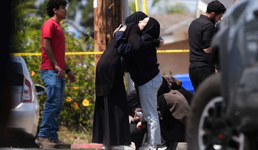 People embrace near the scene of a shooting outside the Islamic Center of San Diego Monday, May 18, 2026, in San Diego. (AP Photo/Gregory Bull)
