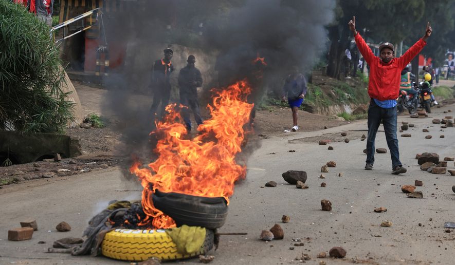 A man demonstrates near a fire during a public transport strike over fuel prices in Nairobi, Kenya, Monday, May 18, 2026. (AP Photo/Andrew Kasuku)