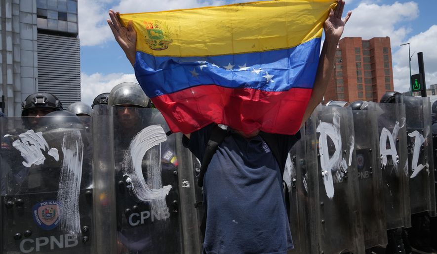 A man holds a Venezuela national flag during a protest calling for justice for Carmen Navas the day after her death in Caracas, Venezuela, Monday, May 18, 2026, a week after the government confirmed that her missing son Victor Hugo Quero had died in custody following his arrest about a year earlier. (AP Photo/Ariana Cubillos)