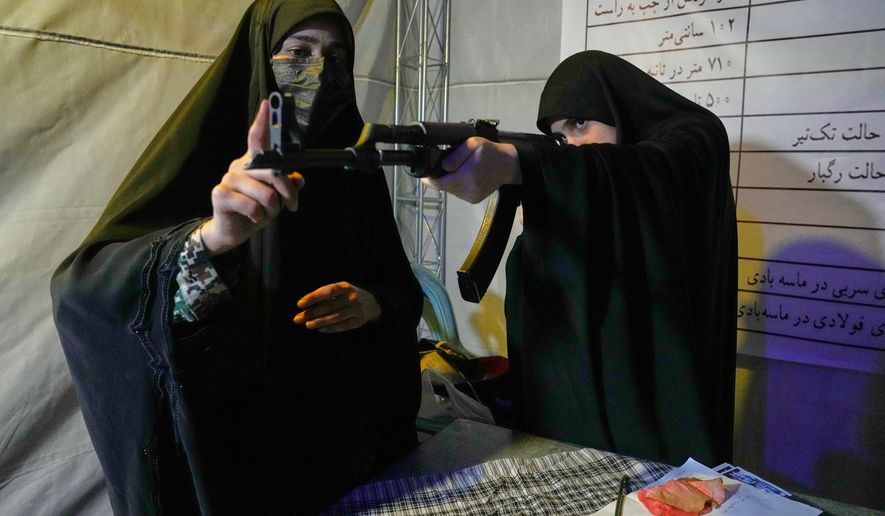 A member of the Revolutionary Guard's volunteer Basij force, left, gives instructions on how to handle a Kalashnikov-style assault rifle during a weapons training class in Tehran, Iran, Tuesday, May 19, 2026. (AP Photo/Vahid Salemi)