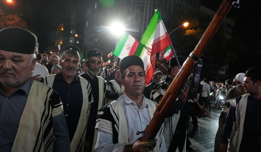 Bakhtiari nomads, wearing traditional dress, chant slogans as one of them holds a gun during a pro-government gathering near the residence where former Iranian Supreme Leader Ayatollah Ali Khamenei was killed in U.S. and Israeli strikes on Feb. 28, in Tehran, Iran, Monday, May 18, 2026. (AP Photo/Vahid Salemi)