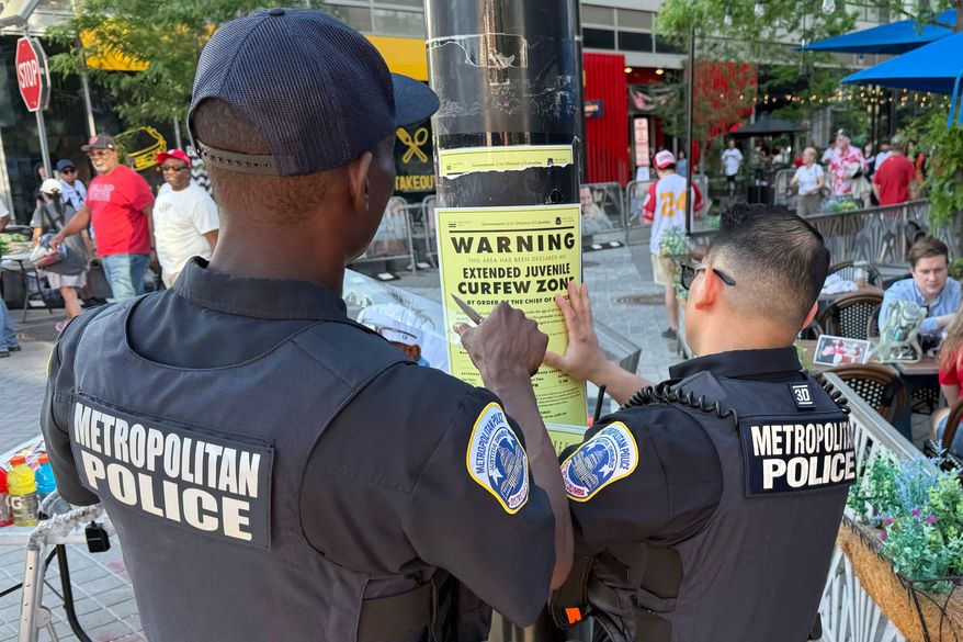 Washington, D.C., Metropolitan Police officers place signage on a light pole in Washington on Friday. April 17, 2026, informing the public that the area near Nationals Park is a designated juvenile curfew zone for youth under the age of 18. (AP Photo/Pablo Martinez Monsivais) **FILE**