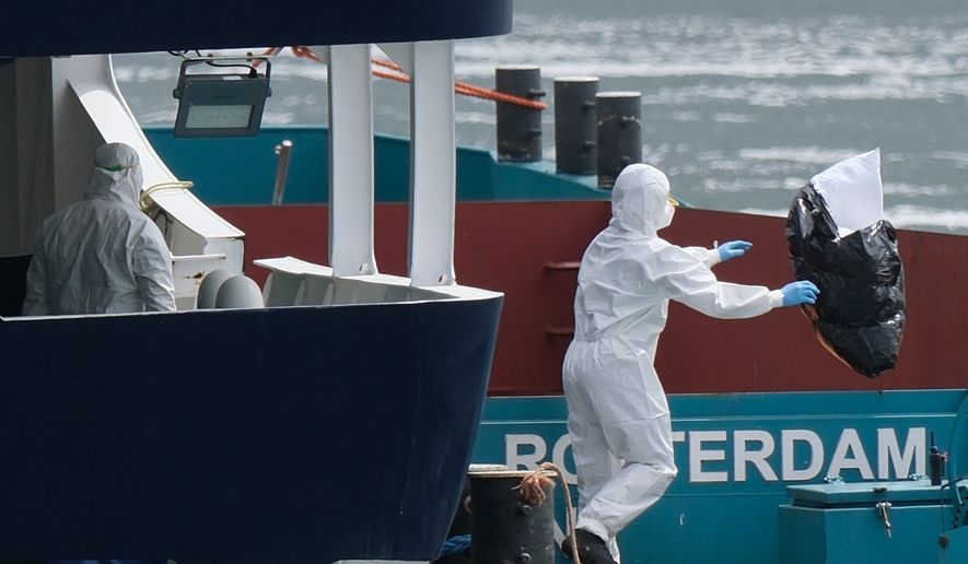 People in protective gear remove waste from the MV Hondius cruise ship after its arrival at the Port of Rotterdam, Netherlands, Monday, May 18, 2026. (AP Photo/Patrick Post)