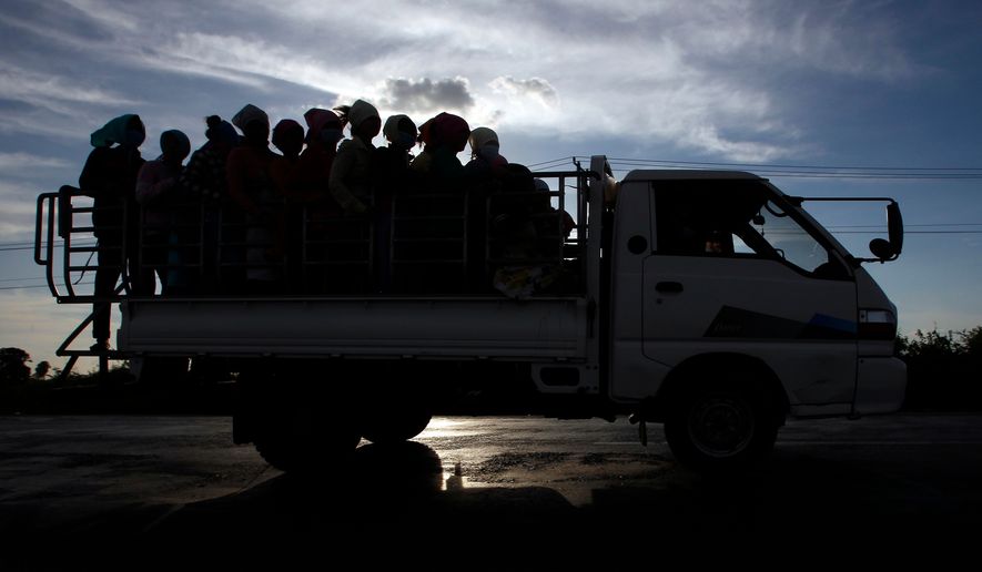 In this Dec. 3, 2018 photo, garment factory workers ride a truck as they go home after a day's work at outside Phnom Penh, Cambodia. (AP Photo/Heng Sinith, File)