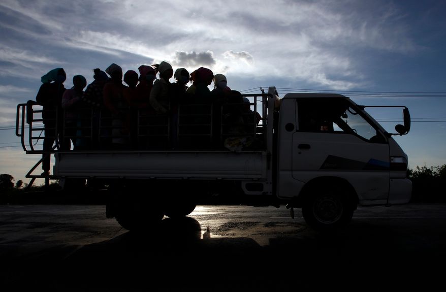 In this Dec. 3, 2018 photo, garment factory workers ride a truck as they go home after a day's work at outside Phnom Penh, Cambodia. (AP Photo/Heng Sinith, File)