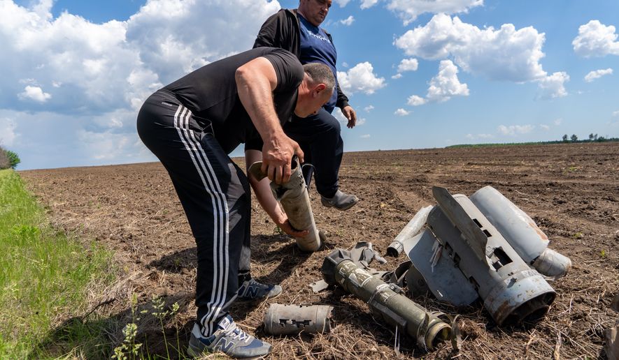 Farmers collect fragments of a Russian missile that hit an agricultural field near the front line in the Kharkiv region, Ukraine, Friday, May 22, 2026. (AP Photo/Andrii Marienko)