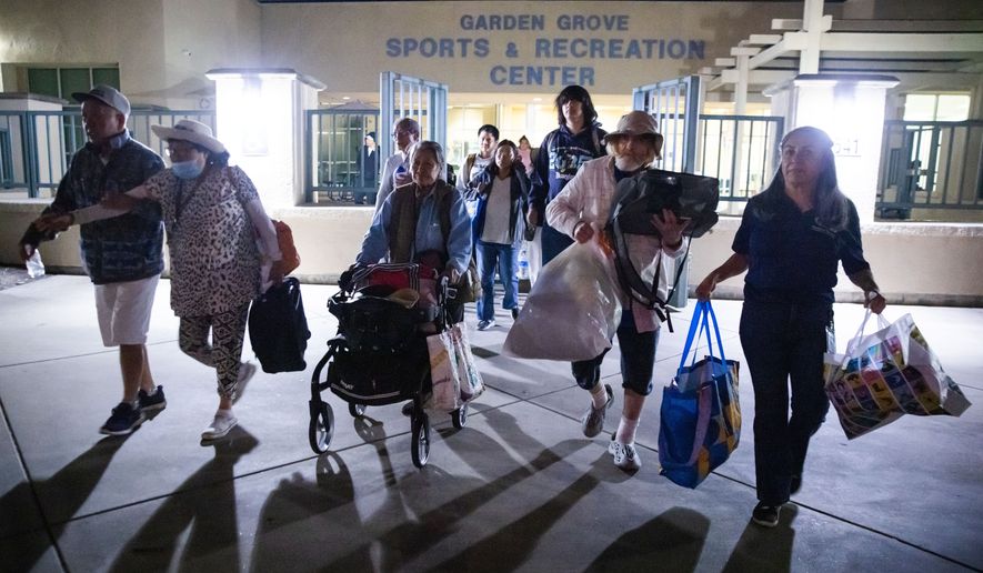 Evacuees from an aerospace chemical plant tank leak move to another shelter after the Garden Grove Sports and Recreation Center closed for the night in Garden Grove, Calif., Friday, May 22, 2026. (AP Photo/Ethan Swope)